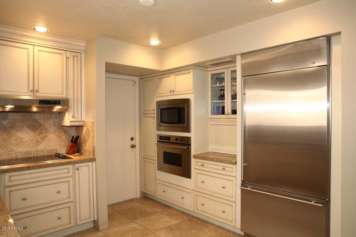 7249 East Maverick Road Scottsdale, AZ 85258 - Photo 14 of 26 a kitchen with white cabinets and stainless steel appliances