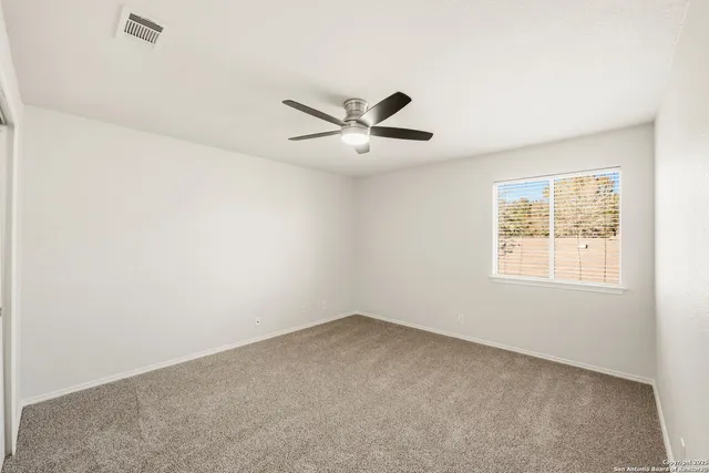 an empty room with a window and a ceiling fan