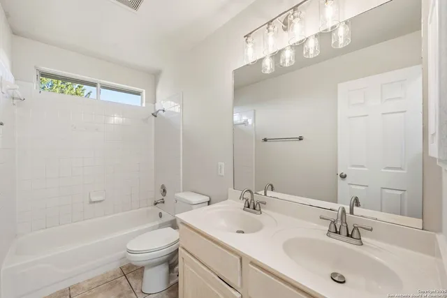 a bathroom with a toilet a sink a mirror a bathtub and vanity