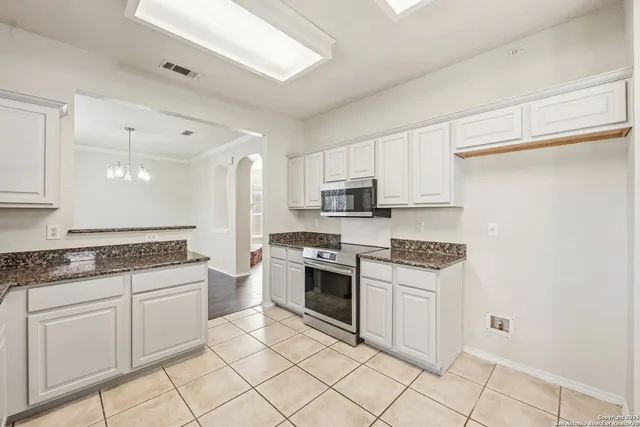 a kitchen with white cabinets and appliances