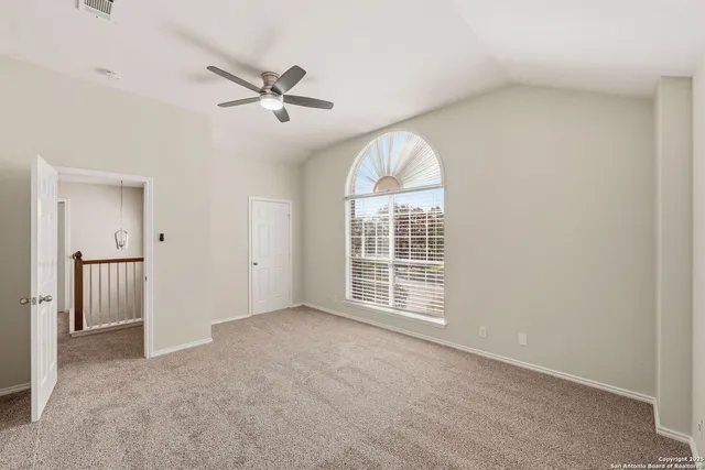 an empty room with a ceiling fan and windows