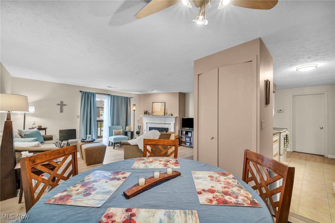 4750 Oak Point Road, Unit 304 Lorain, OH 44053 - Photo 16 of 29 Dining room featuring a fireplace, a ceiling fan, and a textured ceiling