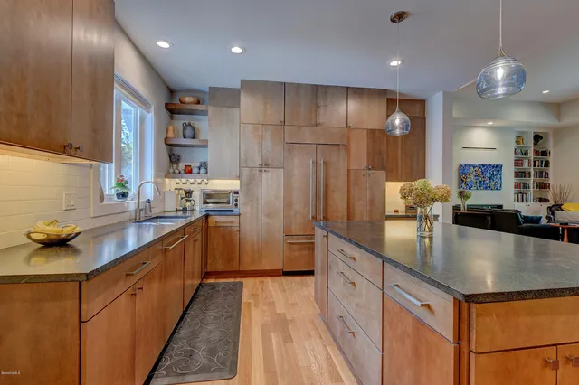 a kitchen with kitchen island granite countertop a sink cabinets and stainless steel appliances