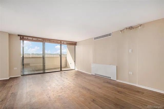 a view of an empty room with wooden floor and a window