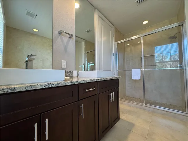 a bathroom with a granite countertop sink a mirror and a shower