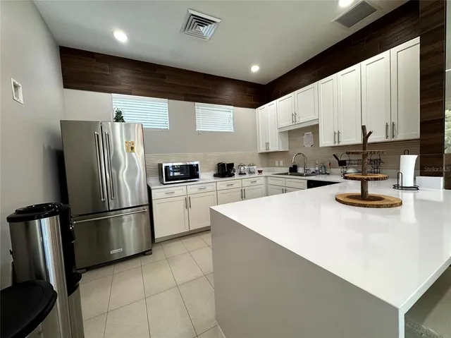 a kitchen with stainless steel appliances granite countertop a refrigerator sink and white cabinets