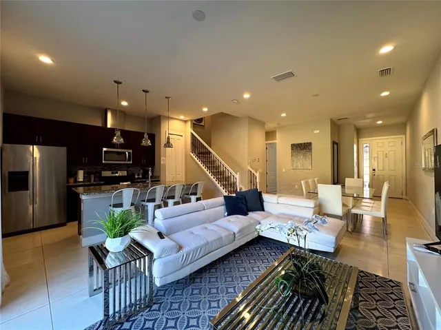 a living room with furniture kitchen view and a wooden floor