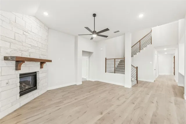 an empty room with chandelier fan and windows