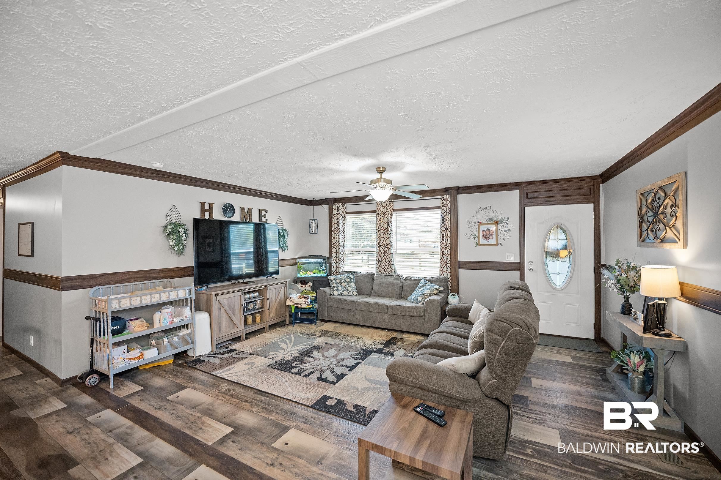 8630 Allison Lane Wilmer, AL 36587 - Photo 6 of 31 Living room with a textured ceiling, crown molding, dark wood finished floors, and ceiling fan