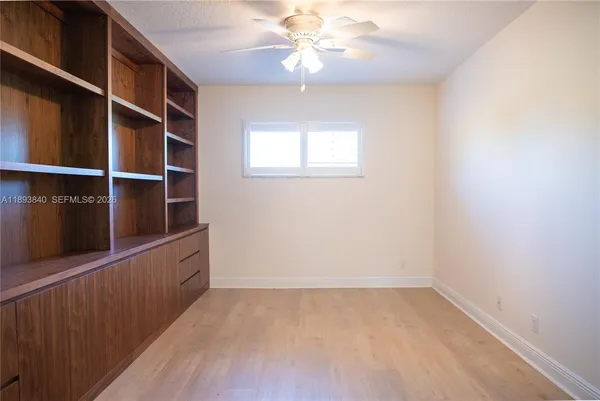 en empty room with windows and chandelier fan