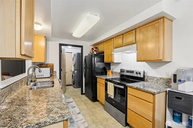 a kitchen with granite countertop a sink stove and refrigerator