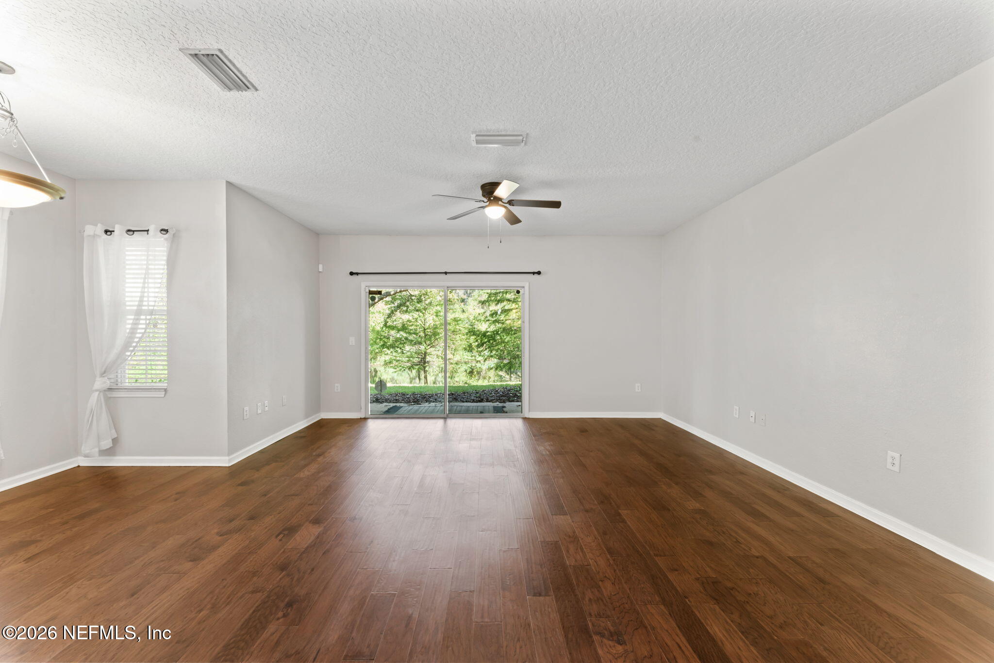 5663 Greenland Road, Unit 1201 Jacksonville, FL 32258 - Photo 18 of 82 an empty room with wooden floor chandelier fan and windows