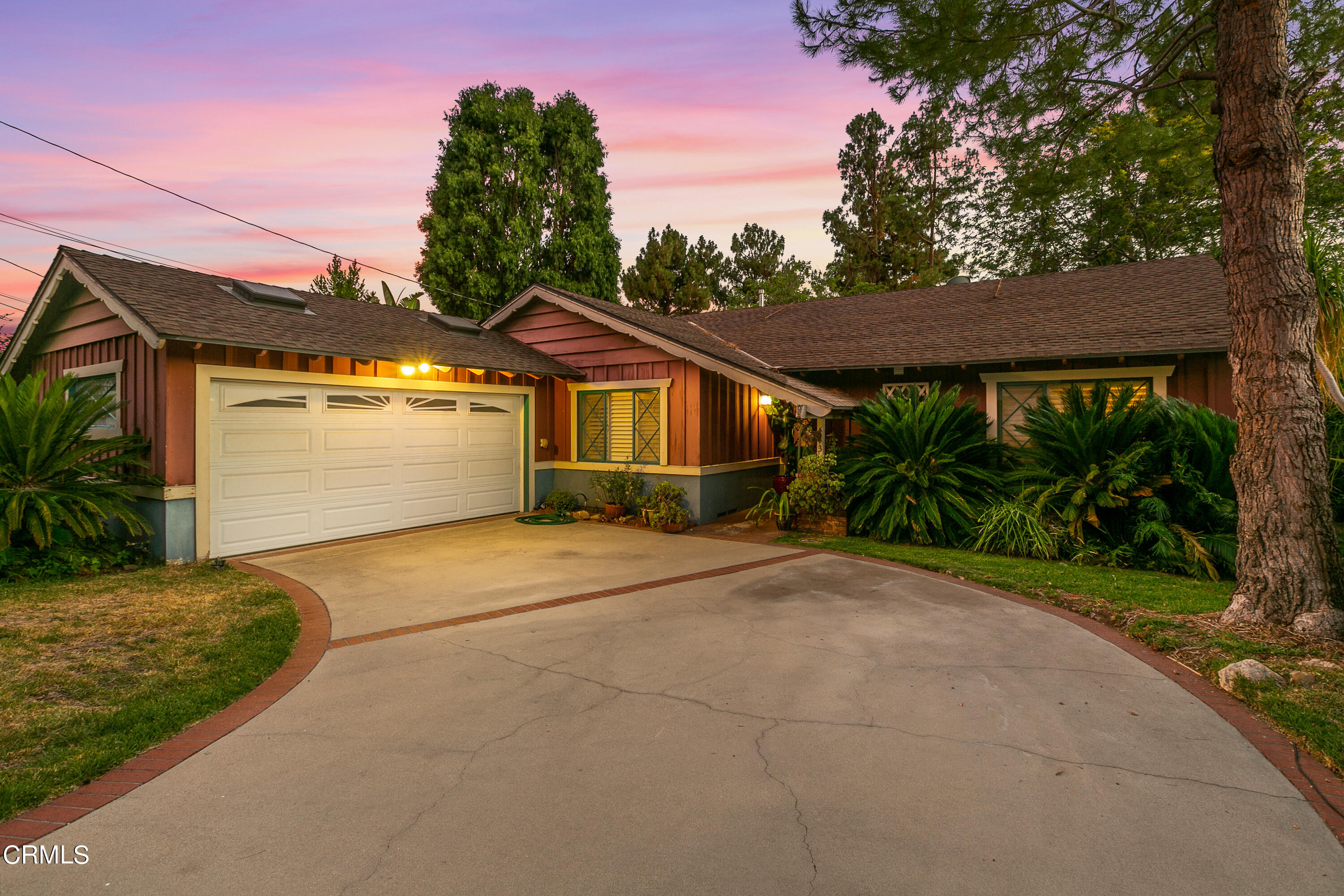 a front view of a house with a garden and trees