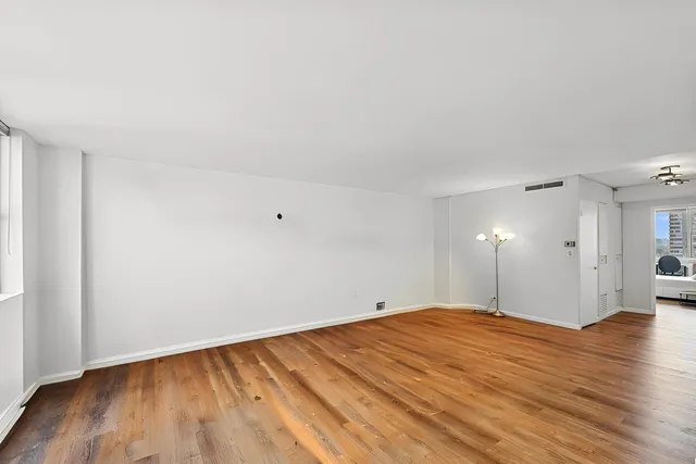 a view of empty room with wooden floor and fan