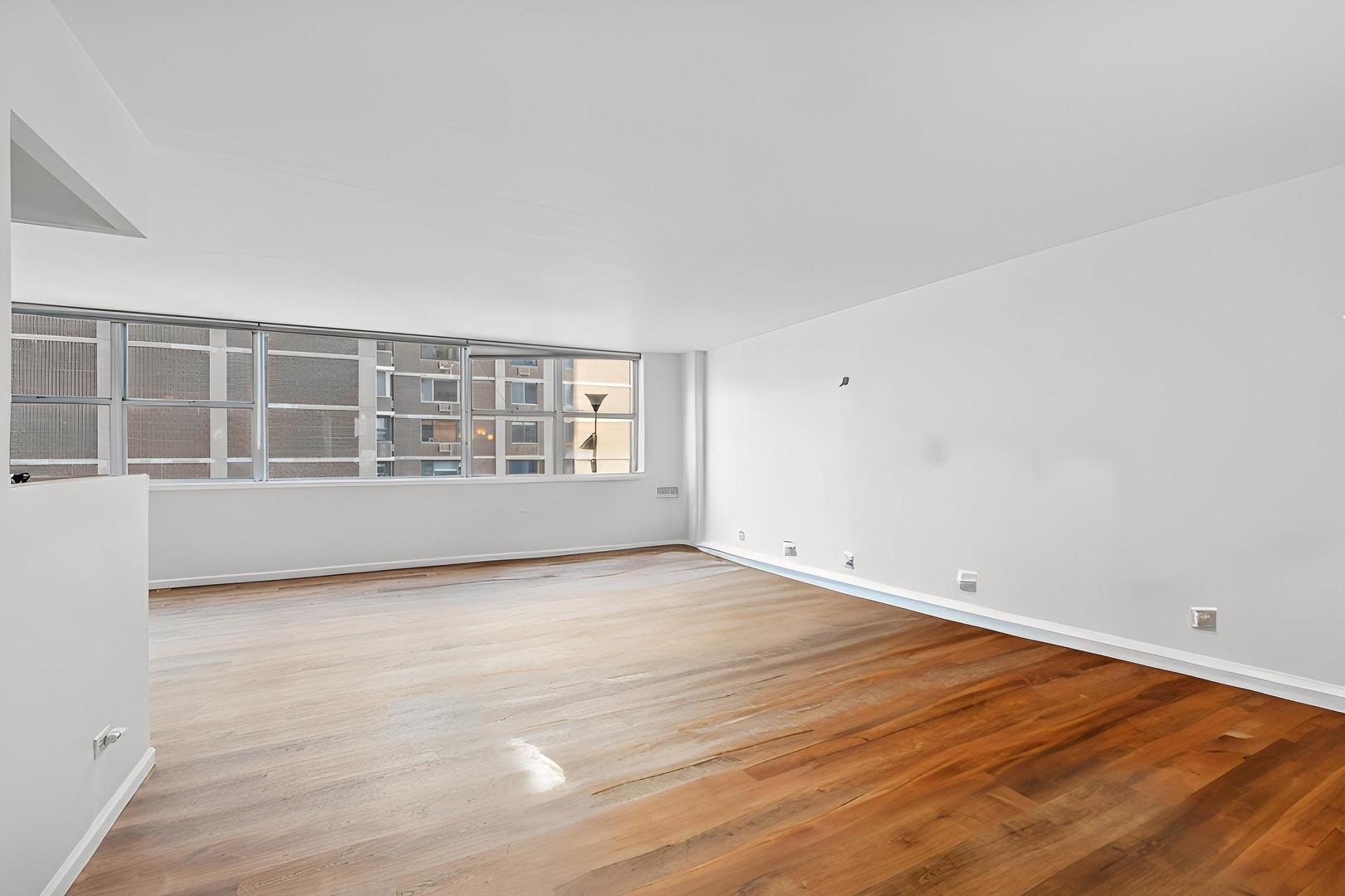 6301 North Sheridan Road, Unit 14E Chicago, IL 60660 - Photo 7 of 20 a view of an empty room with wooden floor and a window