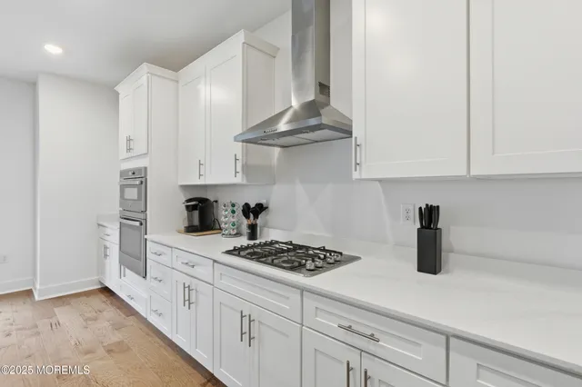 a kitchen with stainless steel appliances granite countertop a sink a stove and a white cabinets