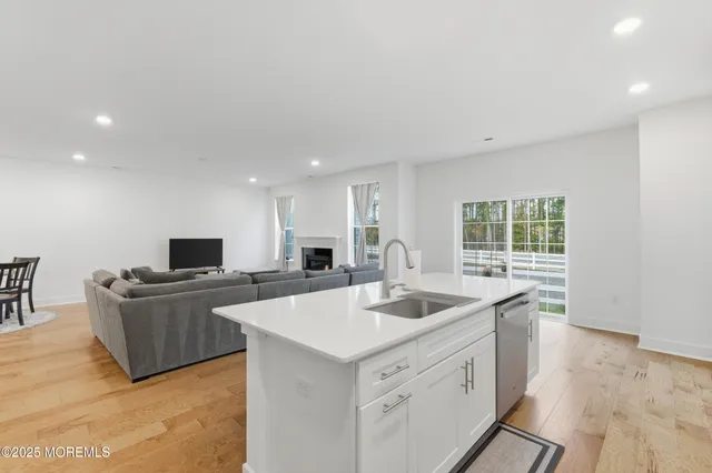a kitchen that has a sink and a stove top oven with wooden floor
