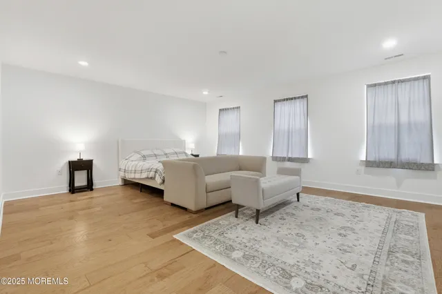 a living room with couches and kitchen view with wooden floor