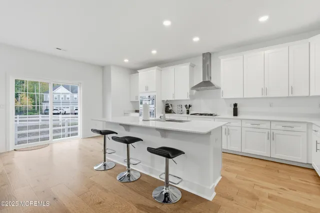 a kitchen with stainless steel appliances granite countertop a sink a stove a refrigerator cabinets and a dining table with wooden floor