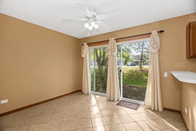 a view of an empty room with window and chandelier fan