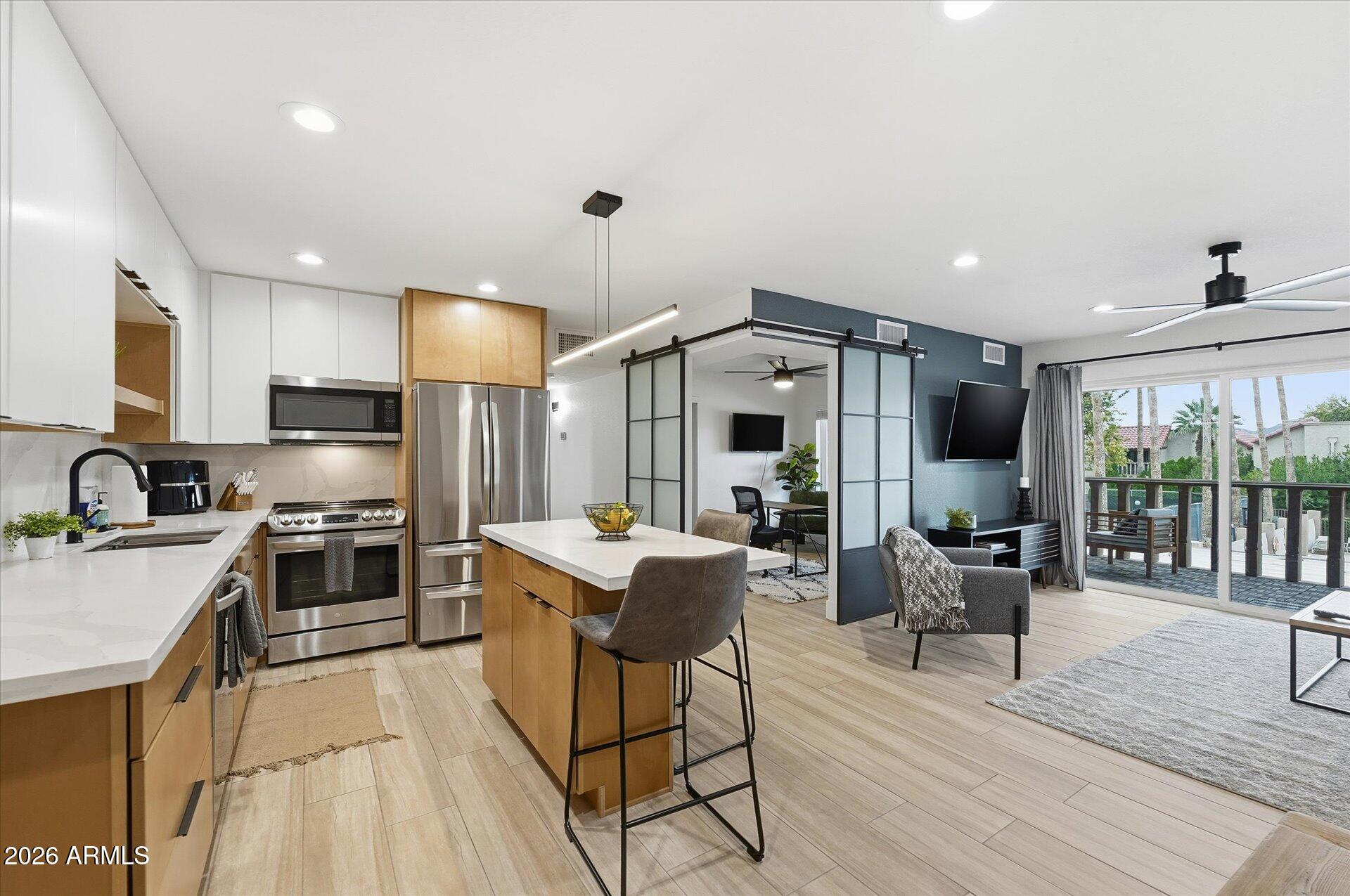 8649 East Royal Palm Road, Unit 239 Scottsdale, AZ 85258 - Photo 2 of 34 a kitchen with stainless steel appliances granite countertop a stove top oven a sink dishwasher a dining table and chairs with wooden floor