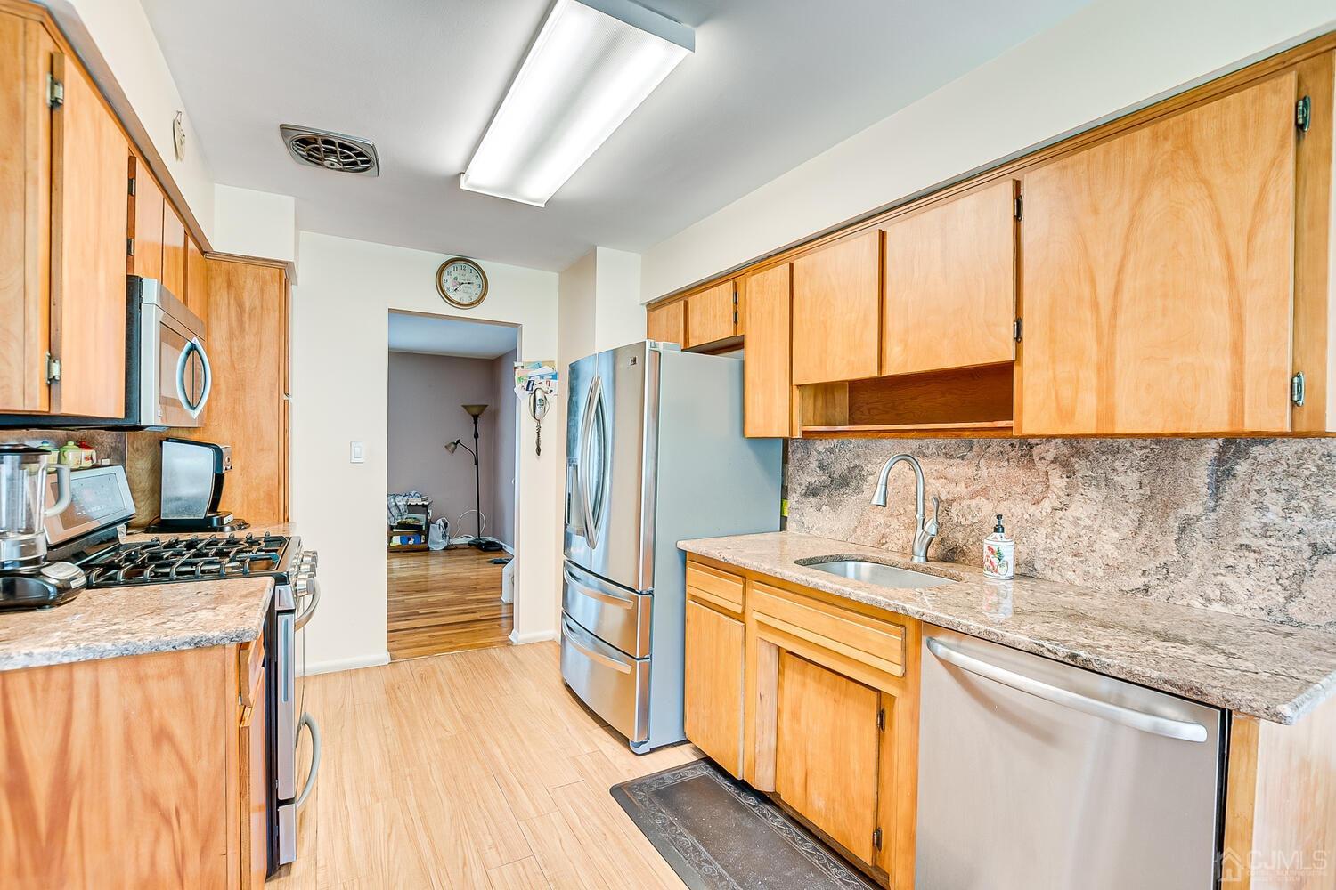 2 Julie Drive Edison, NJ 08820 - Photo 13 of 34 a kitchen with stainless steel appliances granite countertop a refrigerator a sink dishwasher and wooden cabinets with wooden floor