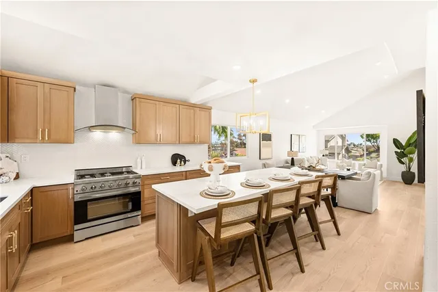 a kitchen with stainless steel appliances granite countertop a stove a refrigerator a microwave a dining table and chairs with wooden floor