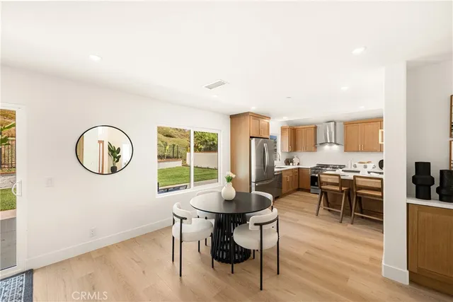 a living room with stainless steel appliances furniture a rug and a kitchen view