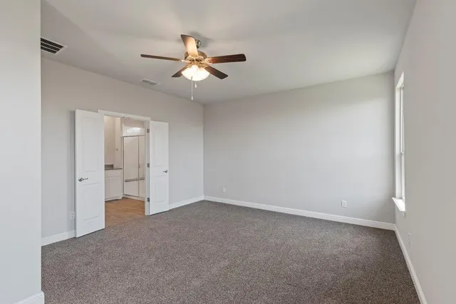 a view of an empty room and a ceiling fan window