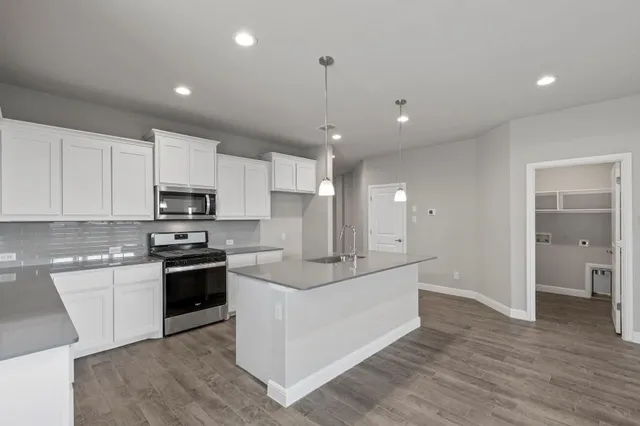 a kitchen with stainless steel appliances kitchen island granite countertop a stove top oven a sink and a refrigerator