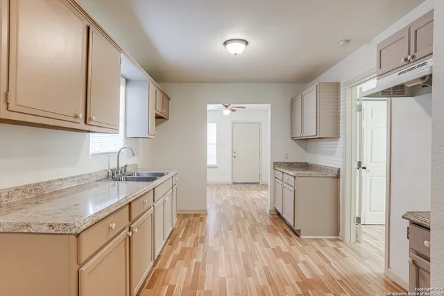 a kitchen with granite countertop a sink a counter space and cabinets