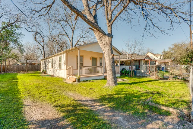 a view of a house with a yard and a large tree