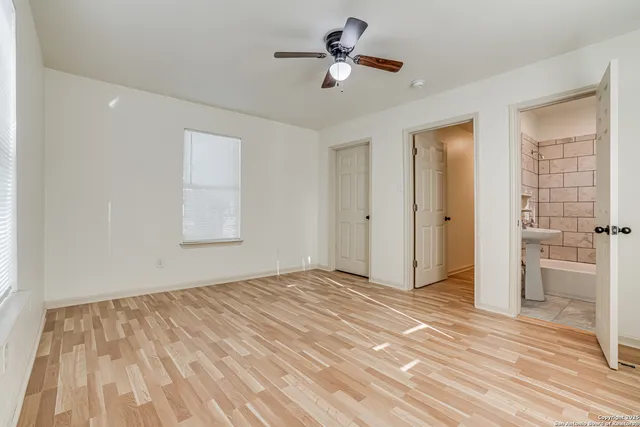 a view of empty room with wooden floor and fan