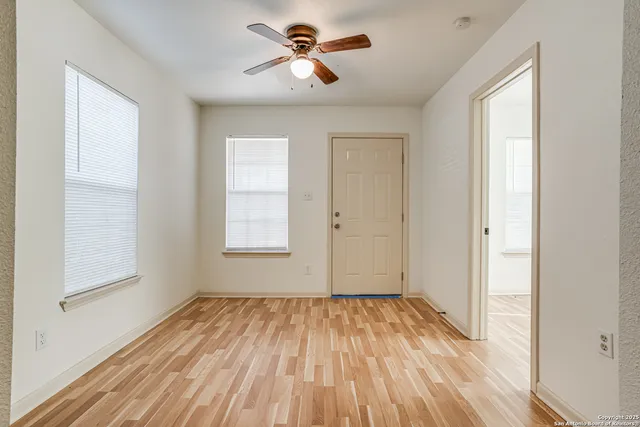 a view of empty room with wooden floor and fan