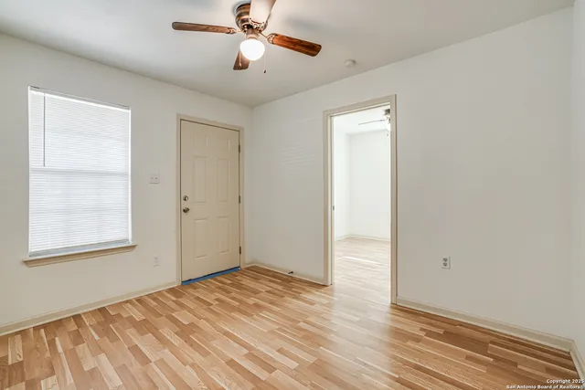 a view of empty room with wooden floor and fan
