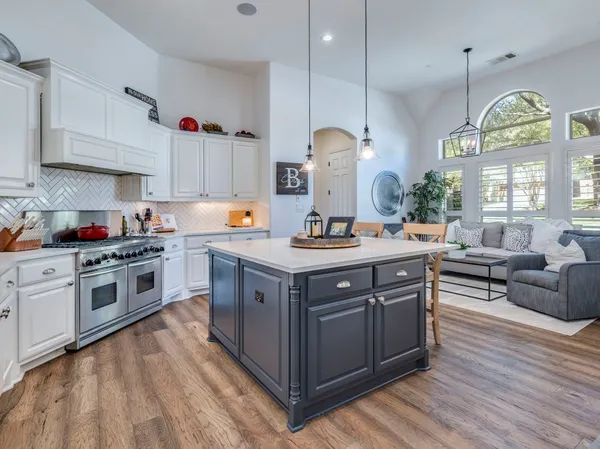 a kitchen with stainless steel appliances granite countertop a stove a sink dishwasher a refrigerator and a dining table with wooden floor