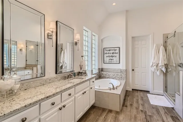 a bathroom with a granite countertop tub sink and mirror