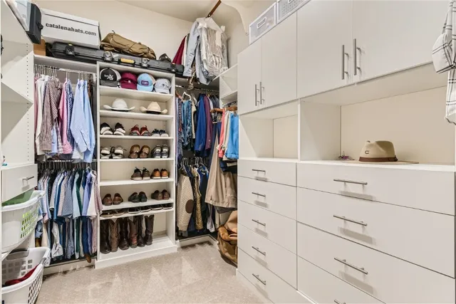 a view of walk in closet with clothes and shoes