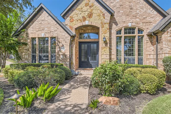 front view of a brick house with a large window and potted plants