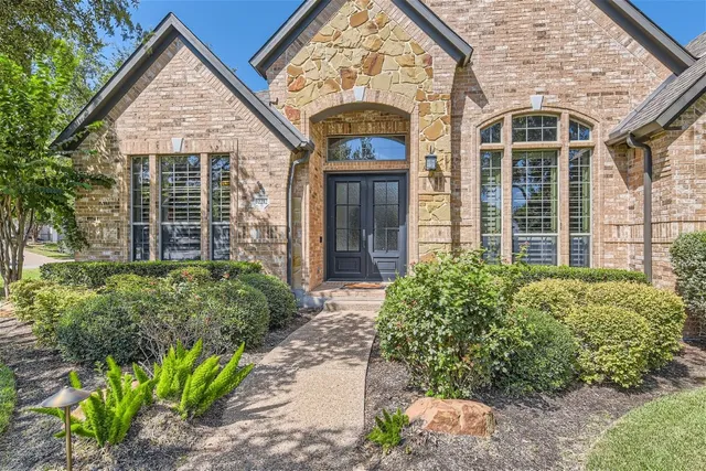 front view of a brick house with a large windows and a flower plants