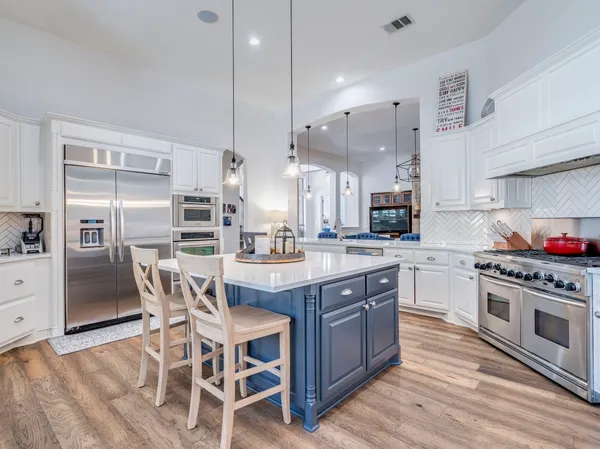 a kitchen with stainless steel appliances kitchen island granite countertop a table chairs stove and cabinets