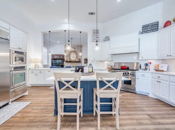 a kitchen with granite countertop a table chairs stainless steel appliances and cabinets