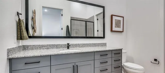 a bathroom with a granite countertop toilet sink and mirror