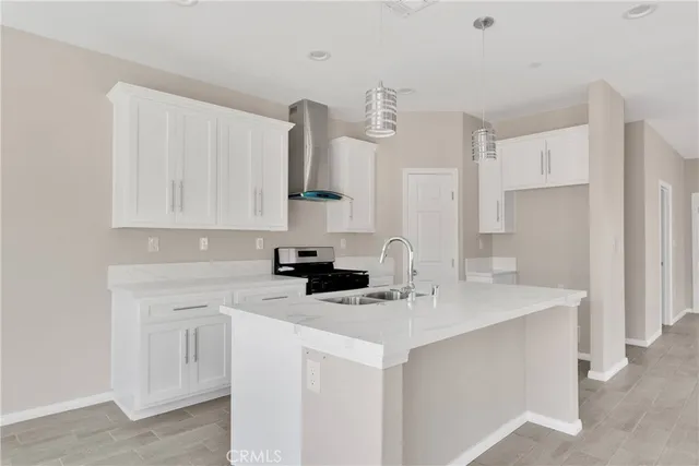 a kitchen with stainless steel appliances a sink a stove a refrigerator a white counter top and white cabinets