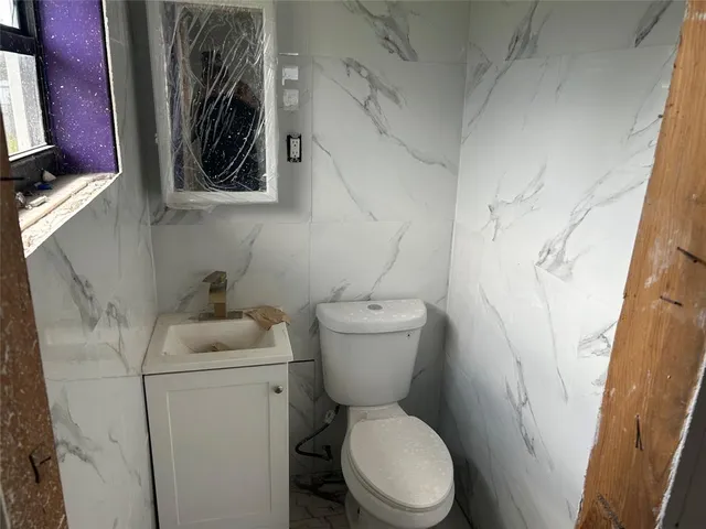 a white toilet sitting next to a white sink and vanity