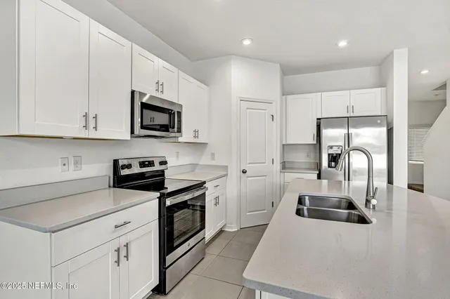 a kitchen with white cabinets and stainless steel appliances