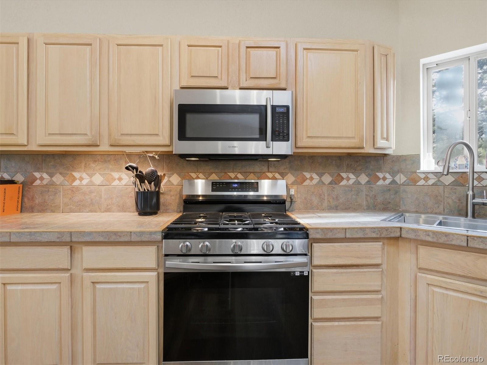 209 Pine Drive Bailey, CO 80421 - Photo 13 of 48 a kitchen with stainless steel appliances granite countertop white cabinets and a stove a oven with white countertops