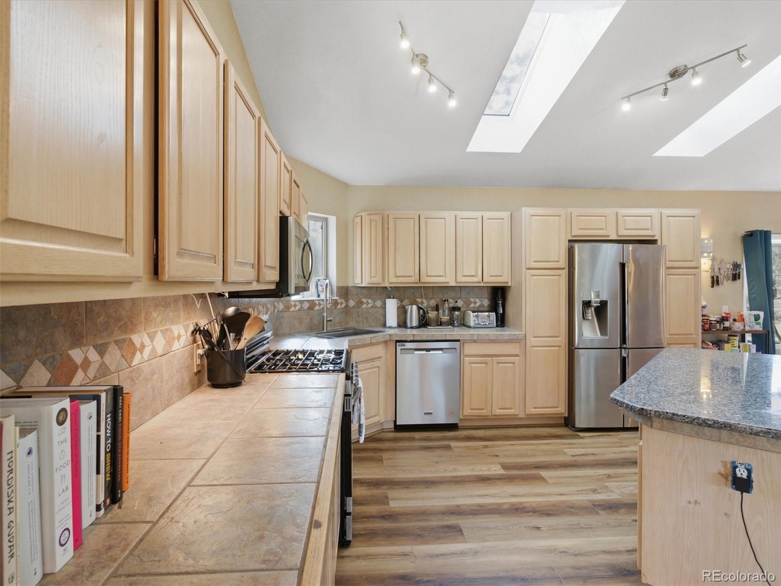 209 Pine Drive Bailey, CO 80421 - Photo 10 of 48 a kitchen with a refrigerator a stove and white cabinets with wooden floor