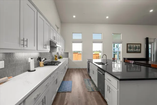 a kitchen with kitchen island granite countertop a sink cabinets and stainless steel appliances