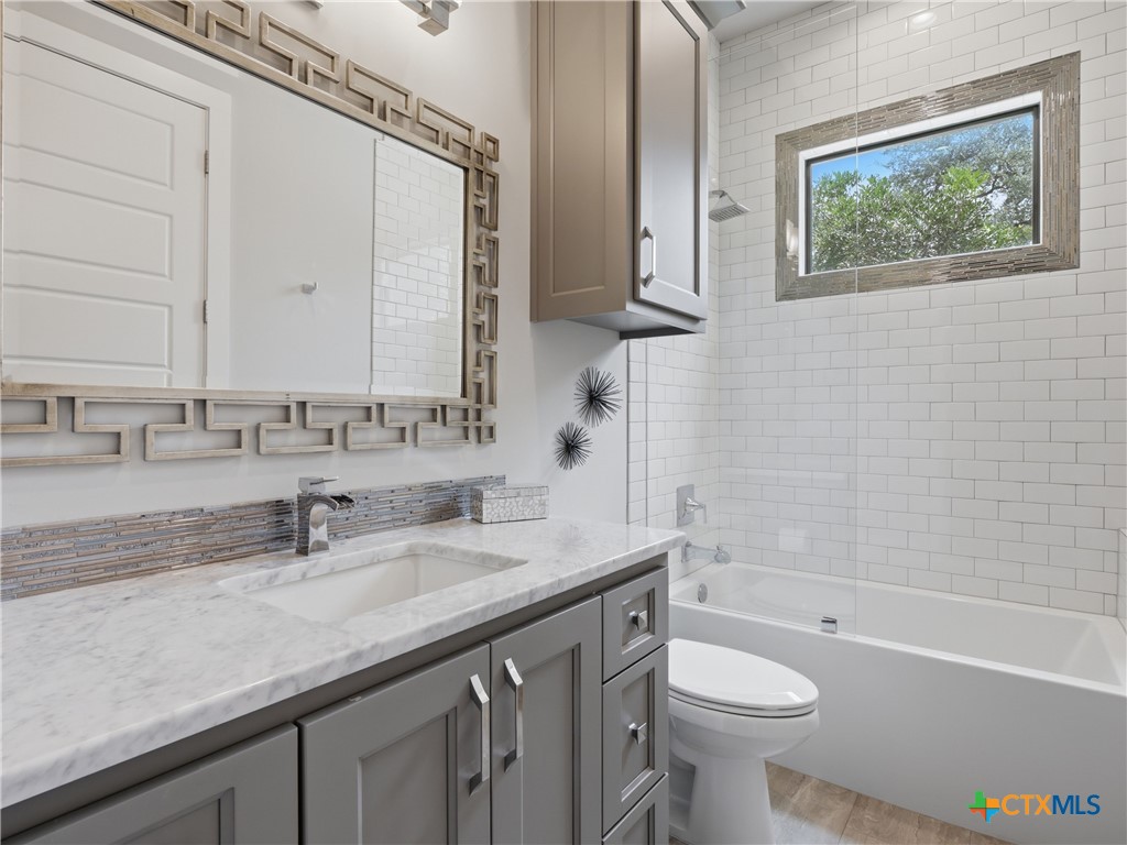 5913 Verden Ridge New Braunfels, TX 78132 - Photo 22 of 48 a bathroom with a granite countertop sink a toilet and bathtub